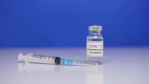 Syringe and Covid-19 Vaccine on Blue Background