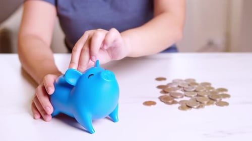 Female hand inserting euro money into piggy bank