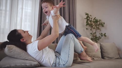 Woman and Child Playing Airplane Game on Sofa