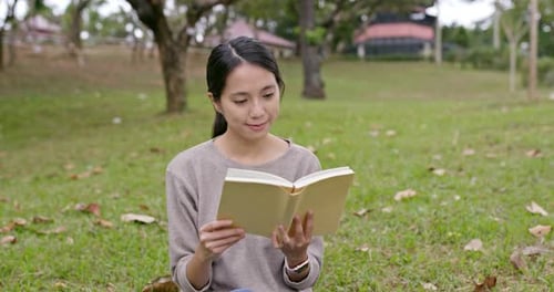 Young Woman Reading Book in Park