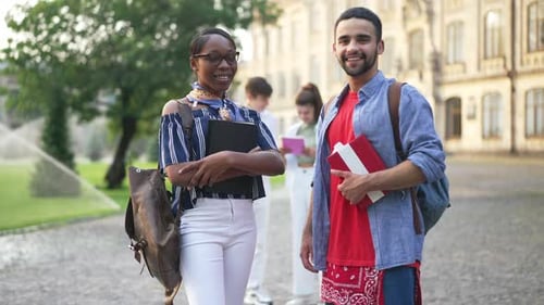 Young Happy Couple of Students Looking at Camera Smiling Standing on Sunny University Yard with
