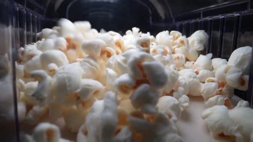 Close up shot of jumping popcorn's during production process in cinema,slow motion