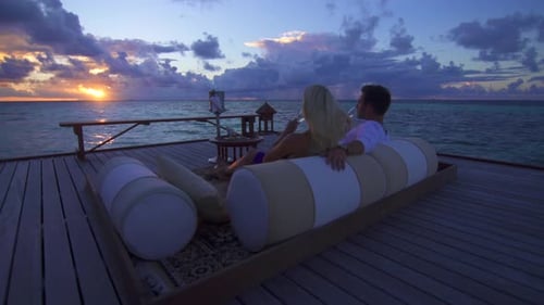 A couple drinking champagne on the beach at a tropical island resort hotel
