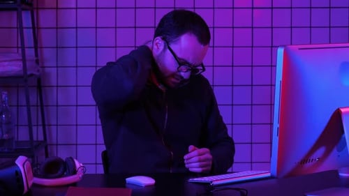 Ein Programmierer, der an seinem Computer arbeitet und Schmerzen im Nacken hat