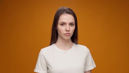 Woman Demonstrating Expressions Against an Orange Background