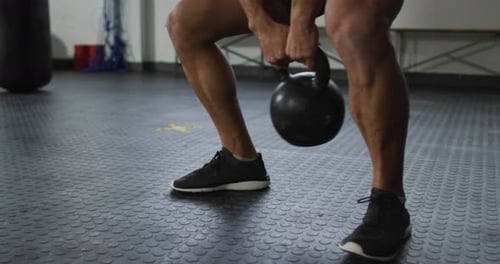 Nahaufnahme eines fitten kaukasischen Mannes, der im Fitnessstudio mit Kettle Bell trainiert