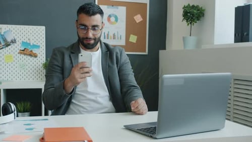 Man Cheering Good News on Smartphone in Office