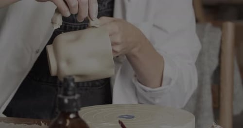 Potter professionnel ajoutant une poignée à une tasse en argile