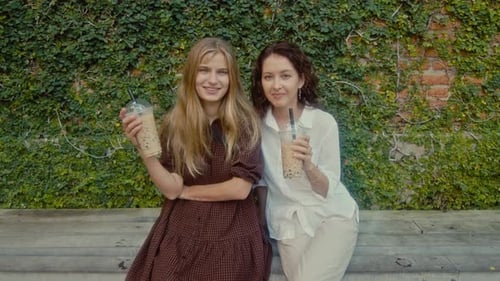 Two Friends Enjoying Drinks Together Outdoors