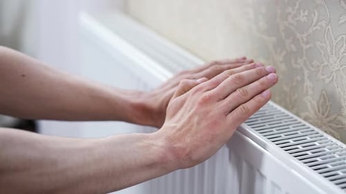 Man Checks the Temperature of the Heating Radiator