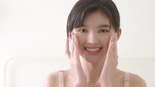 Smiling Woman Applies Skincare to Her Face