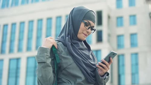 Woman Checks Mobile Device in the City, Smiling