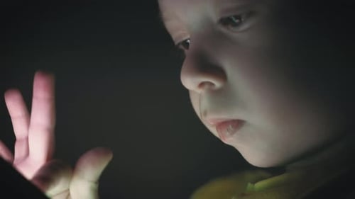 Child Looks at Tablet in the Dark