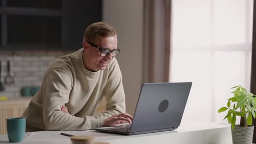 Man Using Laptop at Kitchen Table