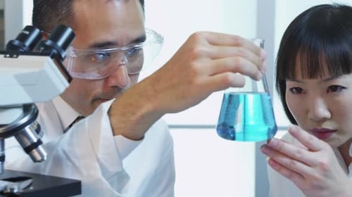 Scientists Analyzing Blue Liquid in a Glass Beaker
