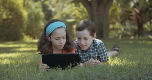 Children Using Tablet Computer Together on the Lawn