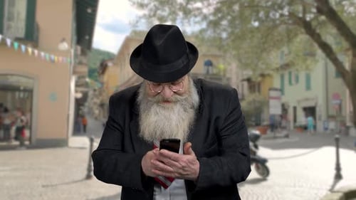 Senior Man Uses Mobile Phone in a European Town