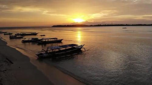 Sunrise over the tropical islands in Southeast Asia. Silent waves rock the boats off the coast.