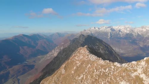 Survoler à basse altitude une crête de montagne révélant le sommet de la montagne avec trois randonneurs. Vue par drone de Julian Alp
