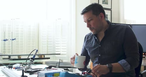 Man Repairs Electronic Components at Desk