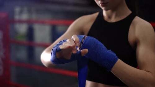 Young Woman Wrapping Hands for Boxing Training
