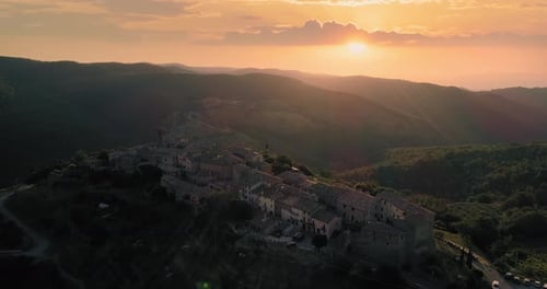 Aerial View Flying Over Rural Medieval Town or Village at Sunset or Sunrise. Back Warm Sun Light
