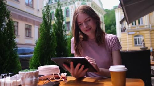 Young Woman Using Tablet Pc in a Cafe on a Summer Terrace