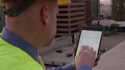 Bauleiter betrachtet Pläne auf dem Touchscreen