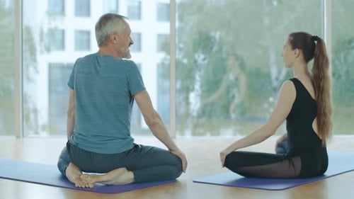 Back View of Happy Confident Man and Woman Sitting on Exercise Mat in Yoga Pose and Talking. Relaxed