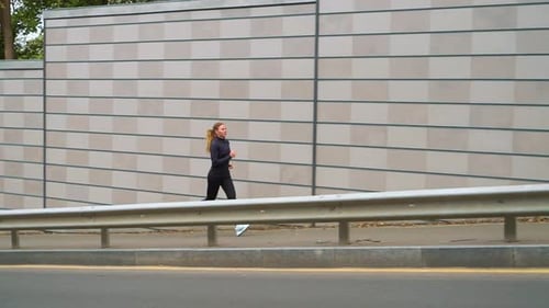Female jogger training near city road in morning