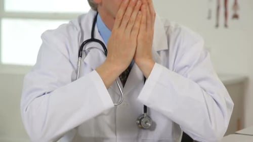 Distressed Doctor Rubbing Face in His Office