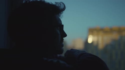 Silhouette of Man Looking out Window at Night