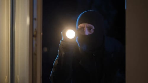 Man in Black Mask with Flashlight at Night