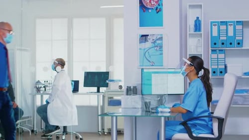 Pushing Disabled Senior Woman in Wheelchair Through Waiting Area