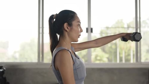 4K Asian athlete woman in sportswear do weight lifting dumbbell at fitness gym.