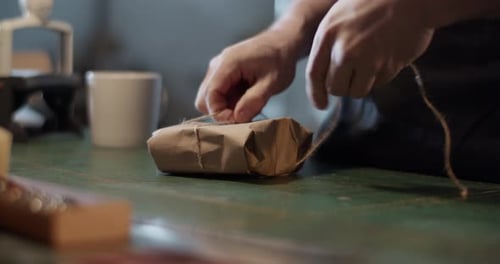 Hands Tying String around Wrapped Brown Package