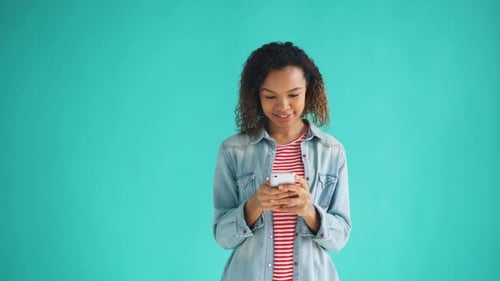 Woman using phone against a blue backdrop