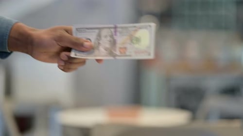 Close Up of African Man Giving Dollars To Caucasian Man