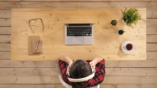 Person Relaxes at Desk With Music and Laptop