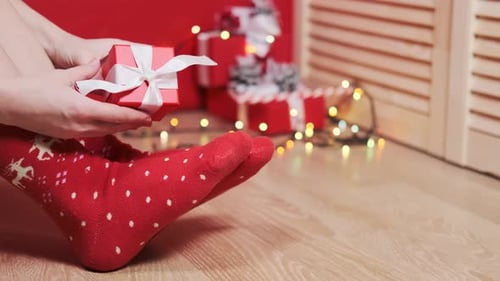 Person Unwrapping a Christmas Gift on a Wood Floor