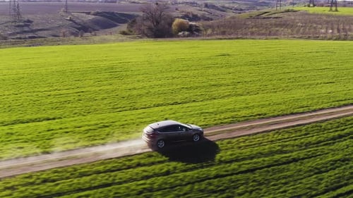 Aerial View of a Car Driving Along a Dusty Dirt Road