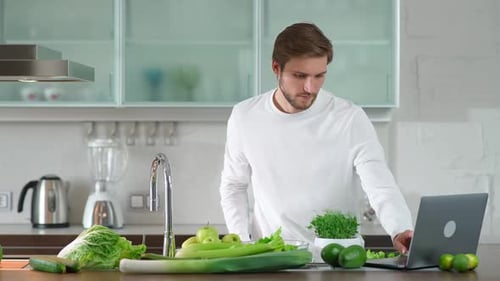 Gesundes Essen Der Mann bereitet in der Küche einen Salat zu, schneidet Kräuter und grünes Gemüse zu, um ein gesundes Gericht zuzubereiten