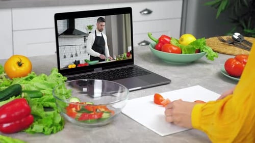 Mujer en la cocina Estudia en línea, videollamada, cámara web, computadora portátil, escucha, el chef le dice al profesor