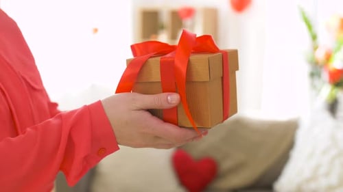 Man Hands Gift to Woman in Living Room