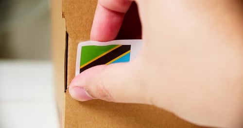 Applying Made in Tanzania Sticker on Box Close Up