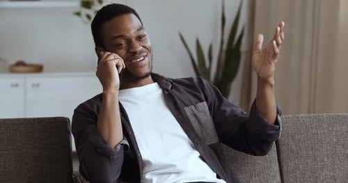 Smiling Young Adult Talking on Mobile Phone at Home