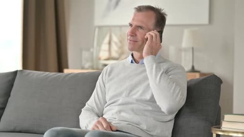 Man Talking on Phone While Sitting on Couch