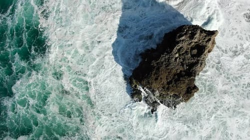 Big Waves Crash Against a Rock Standing in the Ocean, Aerial View Vertically Down