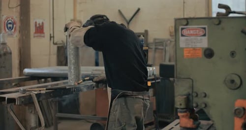 Welder welding metal parts in a workshop