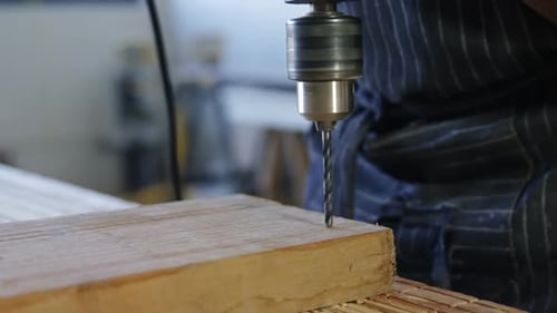 Carpenter drilling wooden plank with machine in workshop 4k